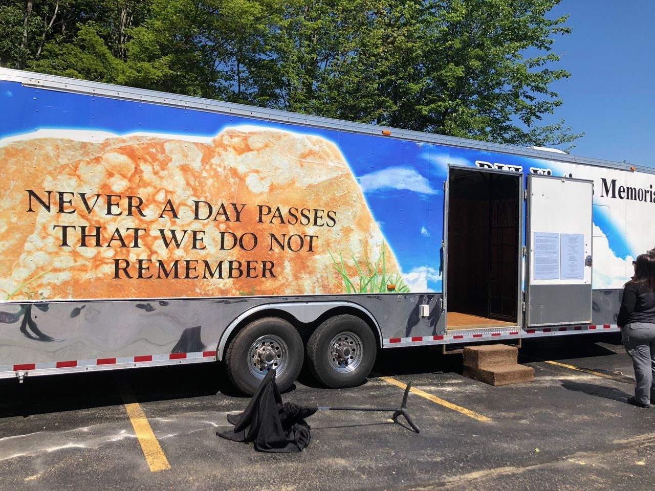 A memorial trailer with the words “Never a day passes that we do not remember” parked in a lot.