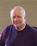 Portrait of a smiling bald man in a purple shirt against a striped background