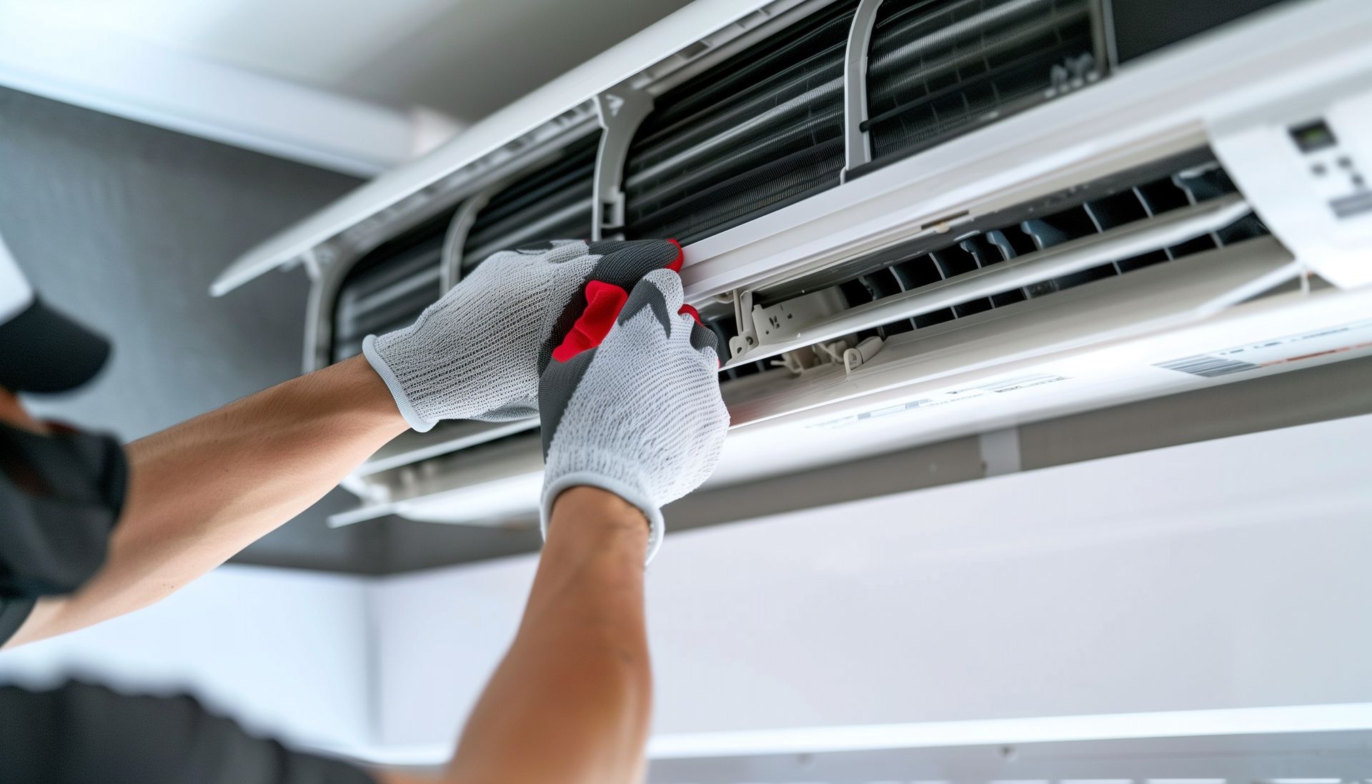 A man is fixing an air conditioner with a screwdriver.