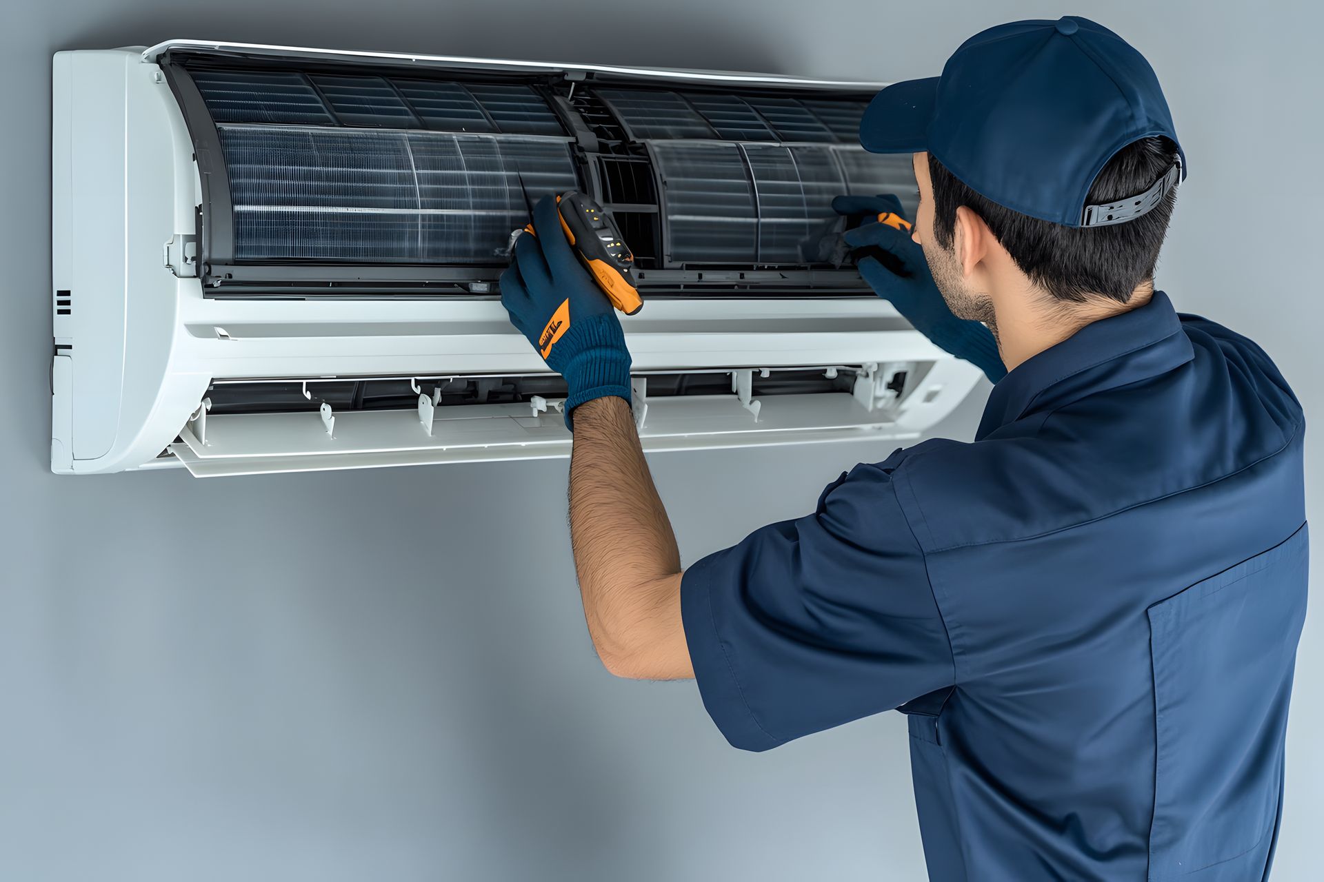 A man is fixing an air conditioner with a screwdriver.