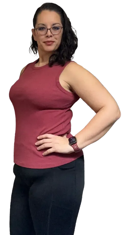 Woman in burgundy top and black pants, hand on hip, wearing glasses and a watch.