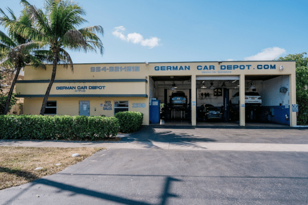 Exterior of German Car Depot auto repair shop in Hollywood, Florida, with open service bays and palm trees.