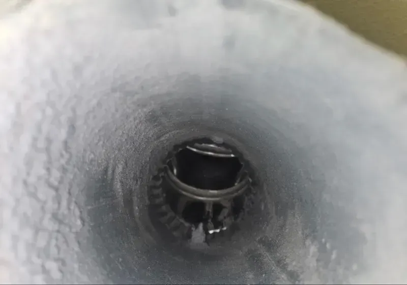 Close-up of a dark circular pipe opening inside a frosty white tunnel