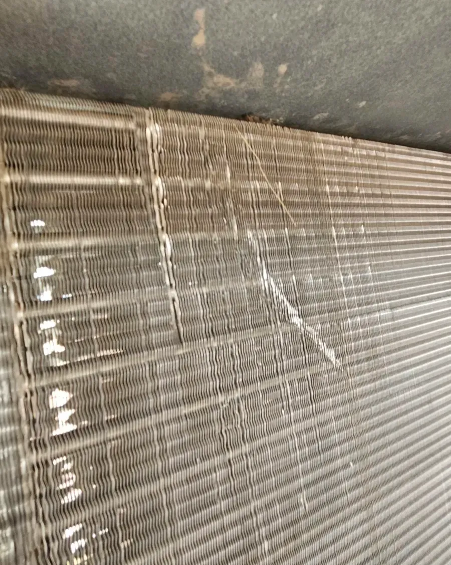 Bent metal window blinds with a broken section and visible dents