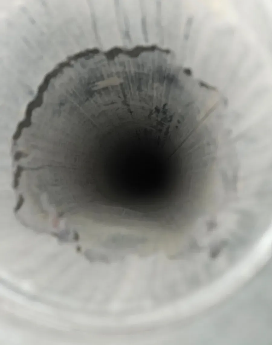 Close-up view down a white corrugated pipe with a dark circular opening.