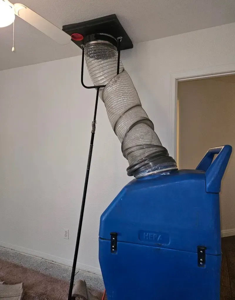 Blue carpet-cleaning machine with a hose ducting out a window in a room