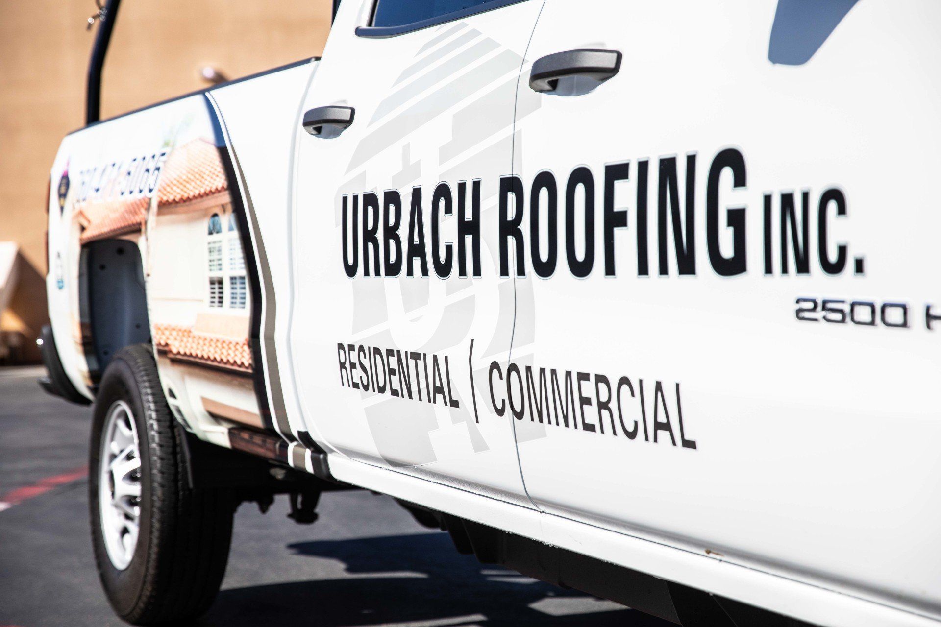 White Urbach Roofing Inc. work truck with company logo parked outside. Residential & Commercial services.