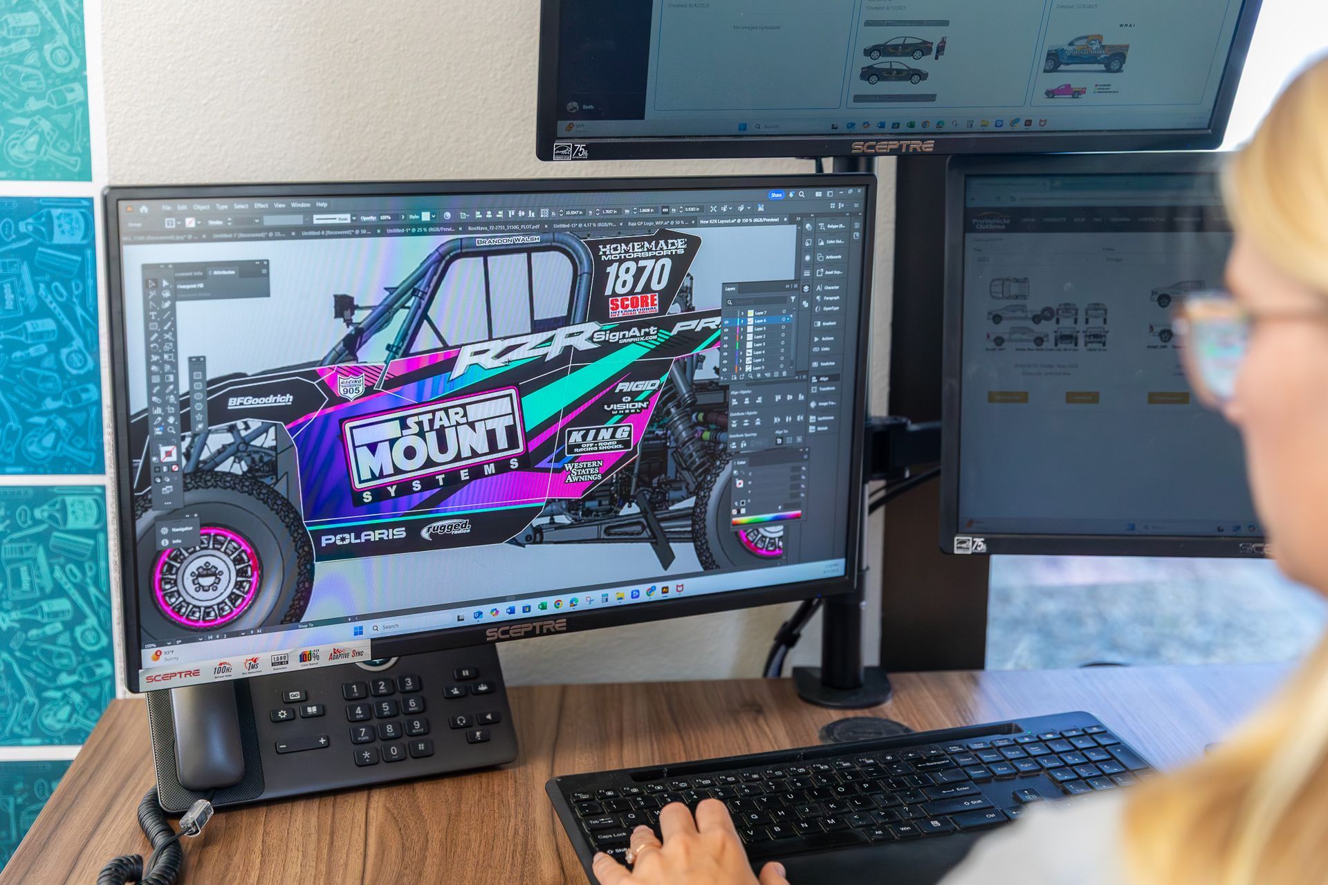 Person editing a colorful off-road vehicle design on a computer monitor at a desk