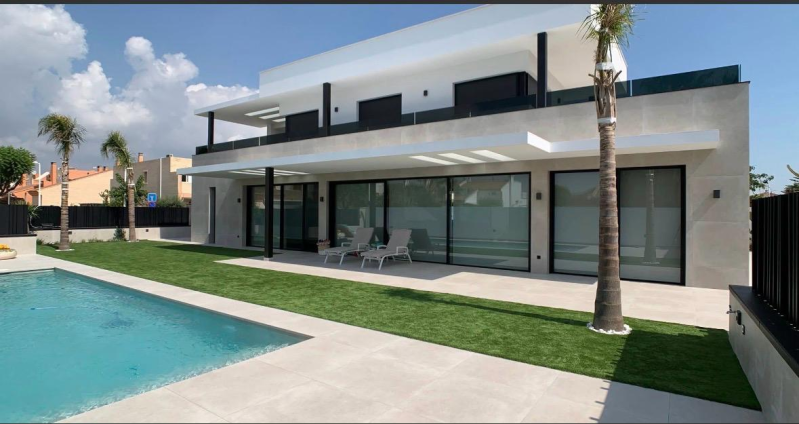 Casa moderna bianca con piscina, patio e palme sotto un cielo parzialmente nuvoloso