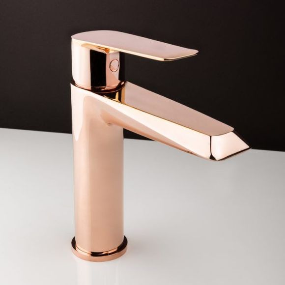 Rubinetto moderno da bagno in oro rosa, su una superficie bianca con uno sfondo scuro