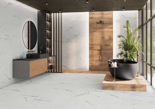 Bagno moderno e minimalista con pareti in marmo, dettagli in legno, uno specchio rotondo e una vasca freestanding accanto a una pianta.