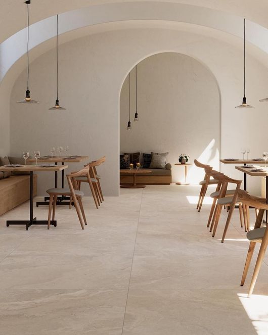 Pavimento in legno a spina di pesce, illuminato dal sole, in una stanza luminosa con sedie disposte lungo i bordi