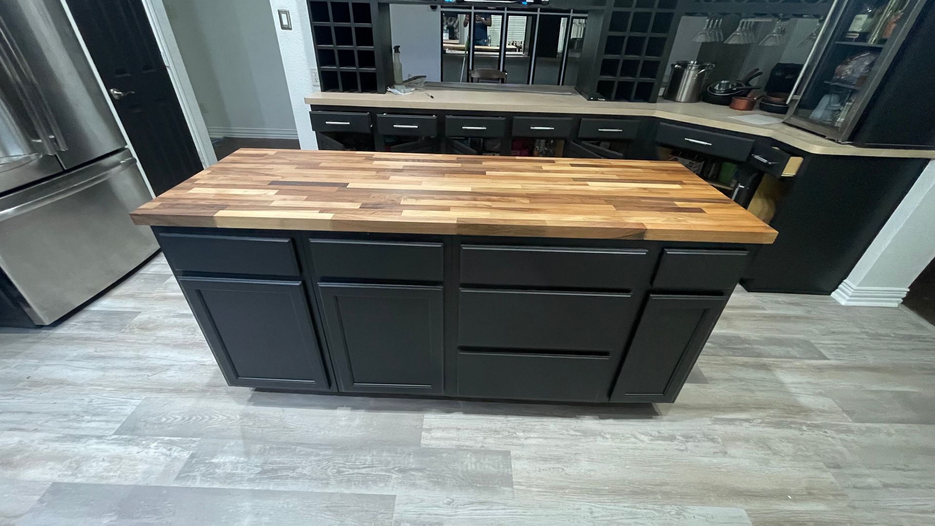 A kitchen with black cabinets and a wooden counter top.