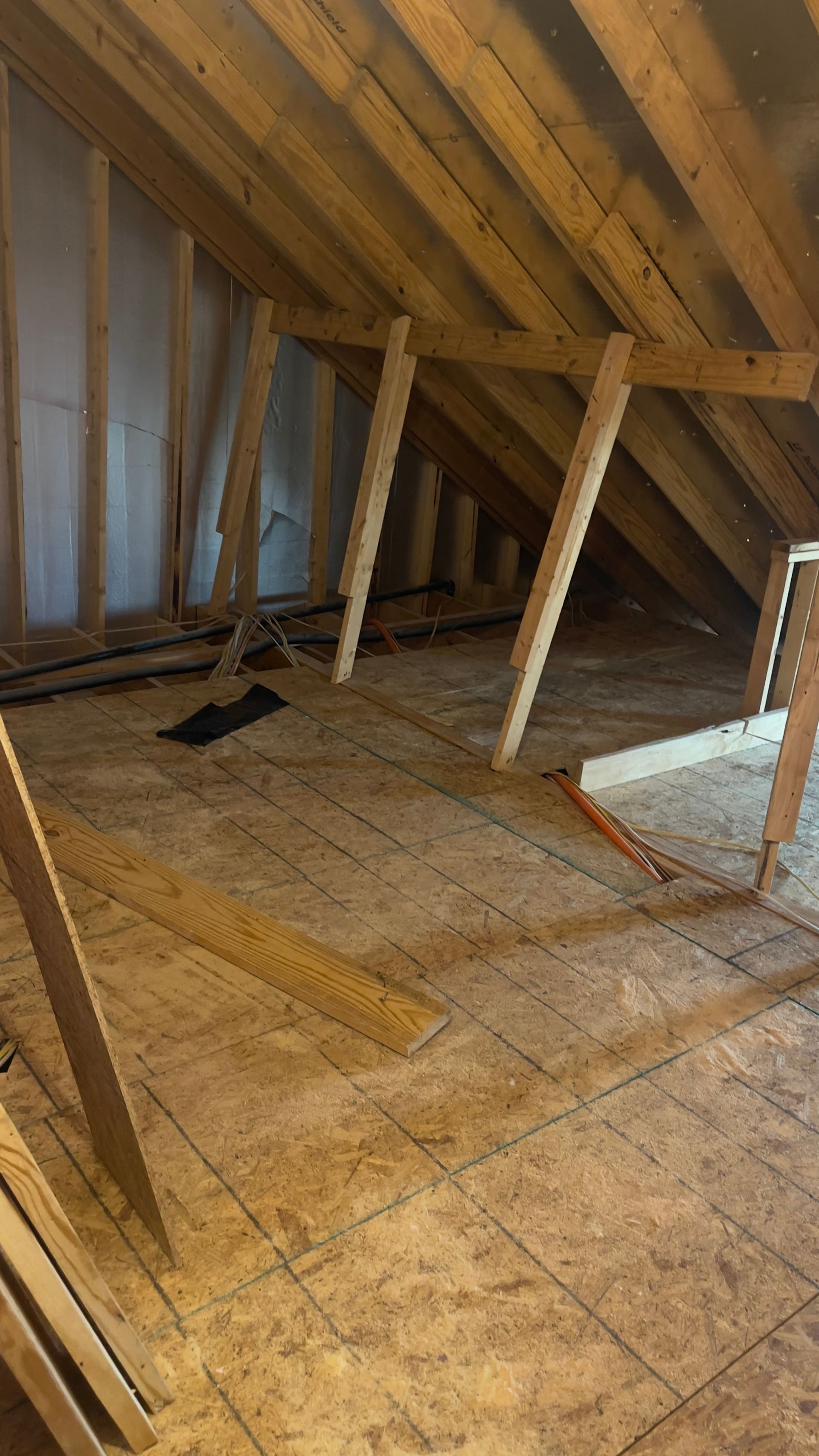 An attic with wooden beams and a wooden floor.