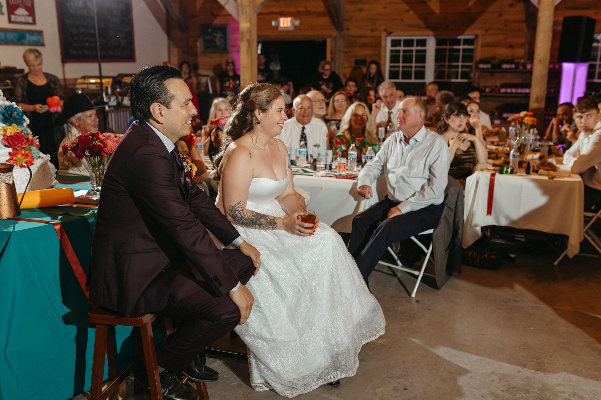 A bride and groom are sitting at a table at a wedding reception.