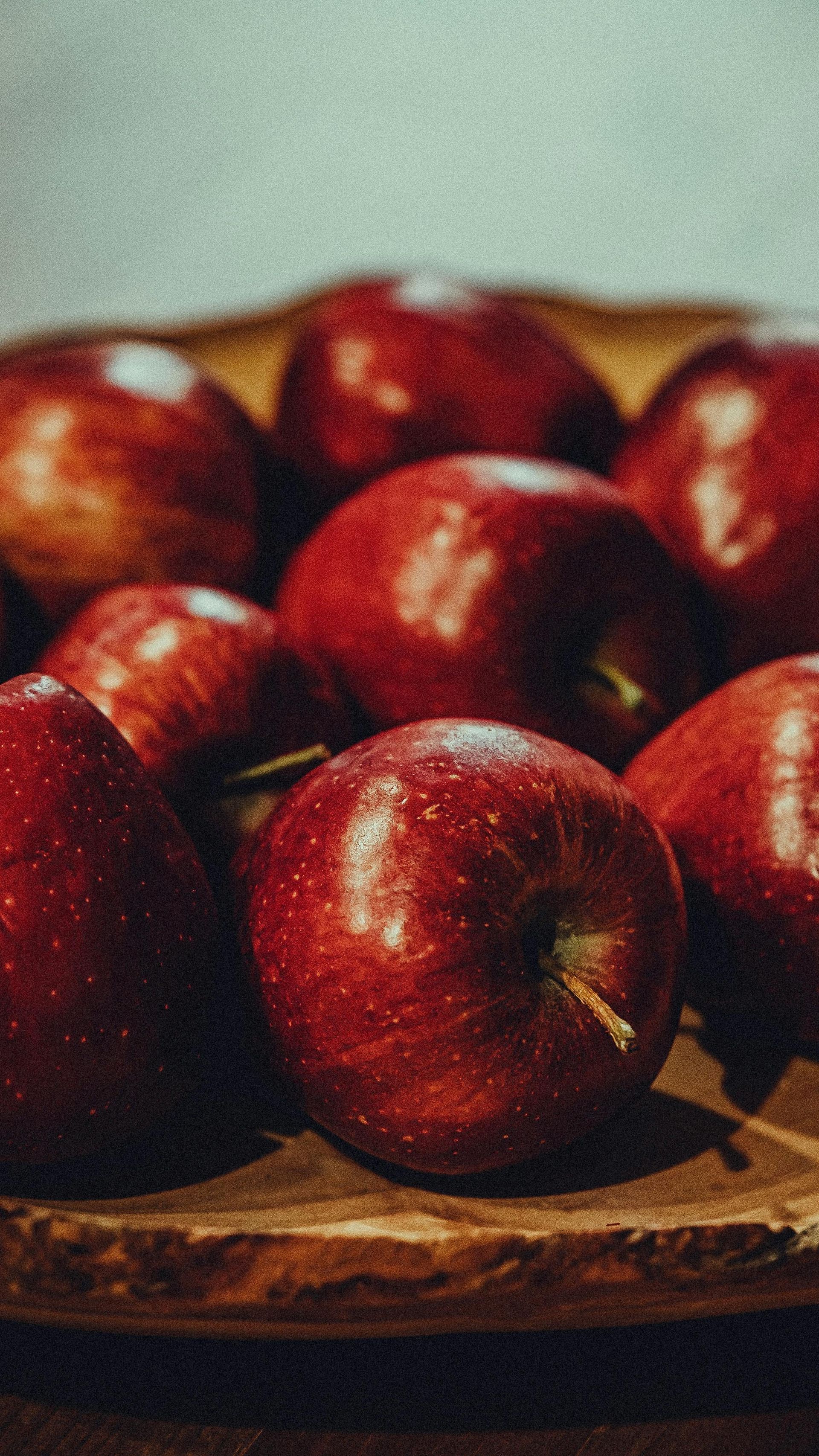 A bunch of red apples are sitting on a wooden cutting board.