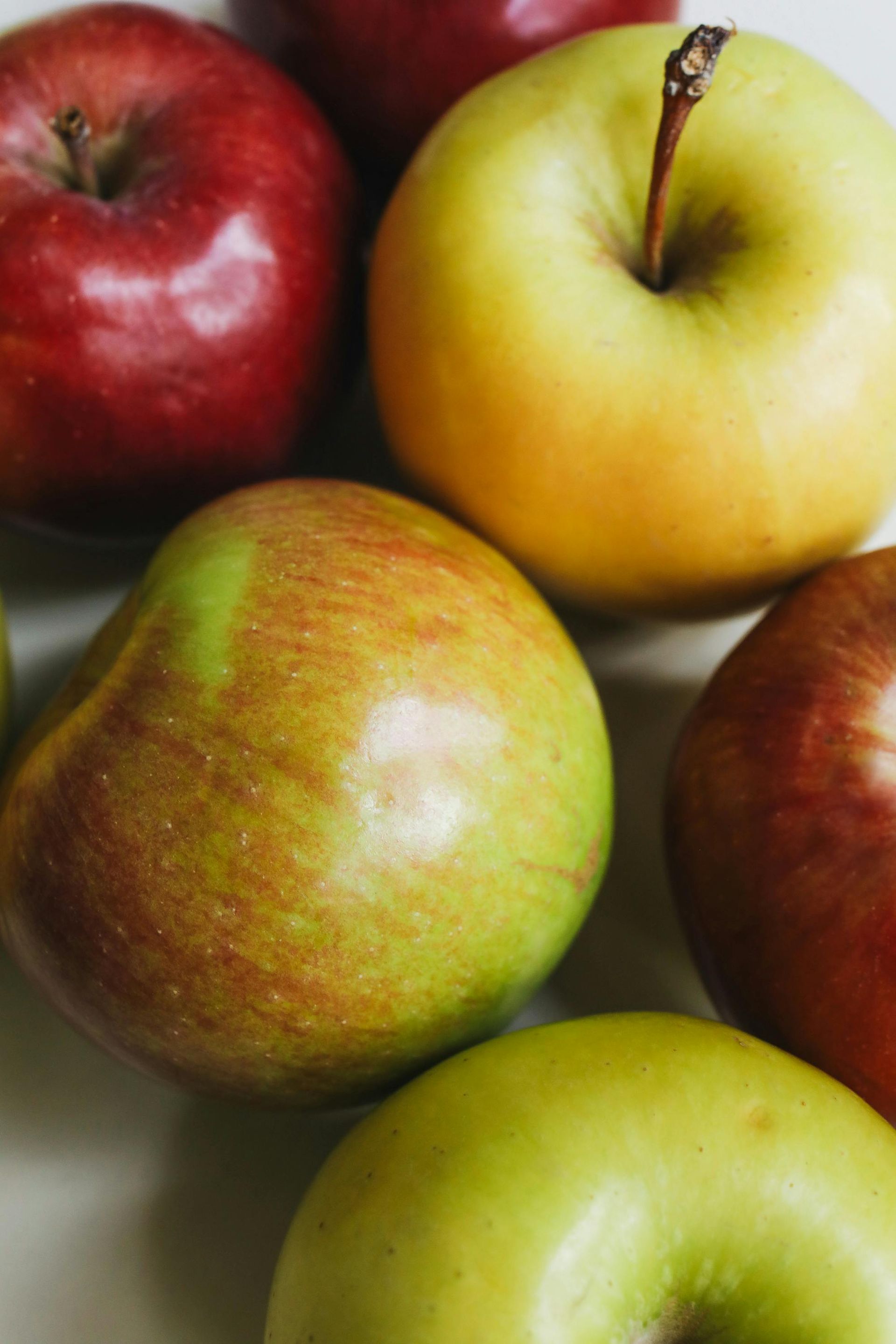 A bunch of apples are sitting on top of each other on a table.