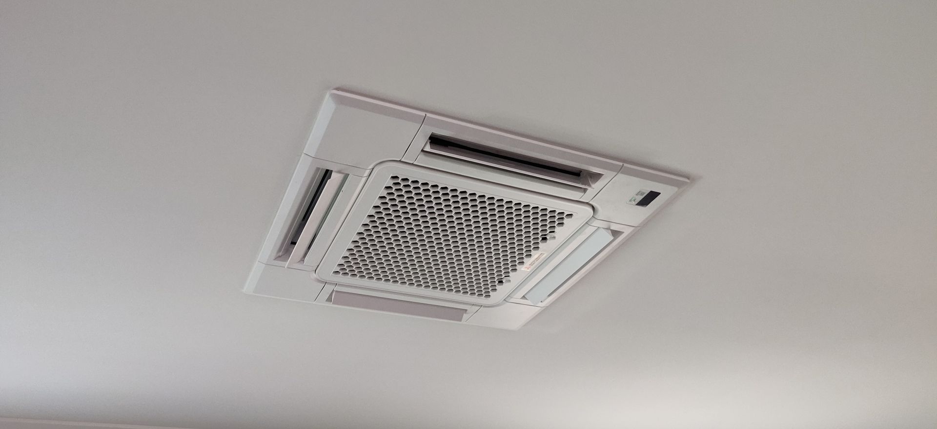 White ceiling-mounted air conditioning unit against a white ceiling in Nowra