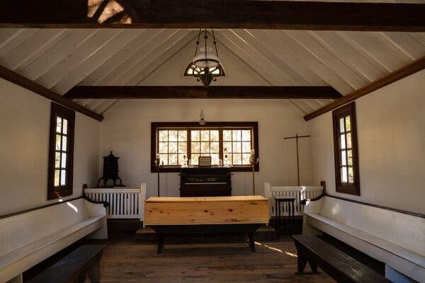 Cozy cabin sitting room with white benches, wood chest, window, and hanging lantern.