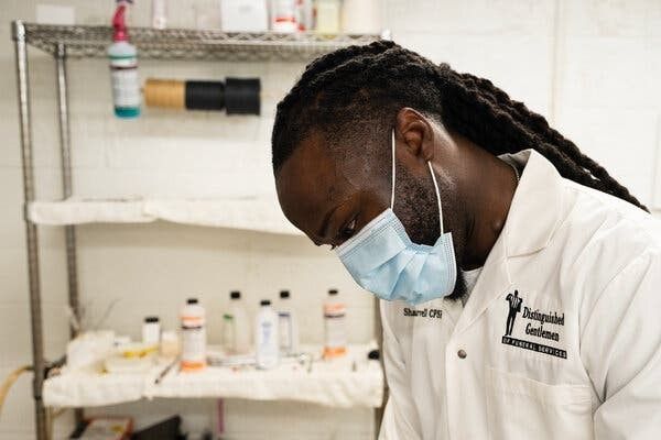 Lab technician in a white coat and mask working at a lab bench with bottles and equipment