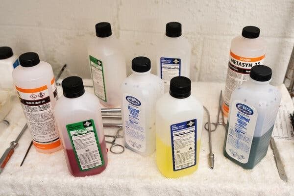 Assorted cleaning product bottles and a small tool arranged on a towel.