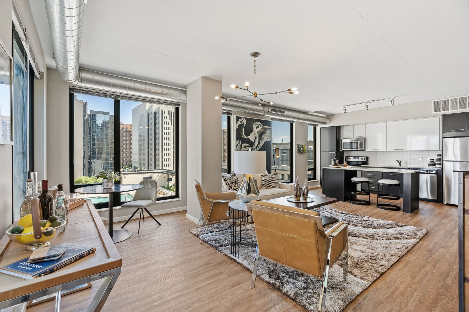 A living room with a couch , chairs , a coffee table and a kitchen.