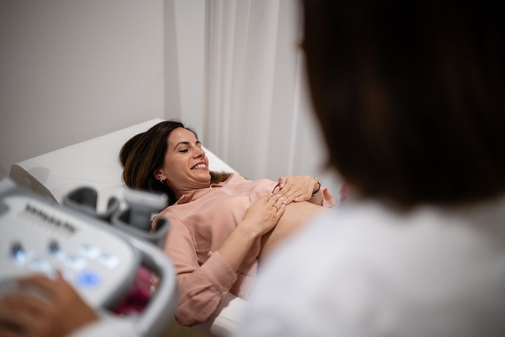 Woman reclines on an exam table during an ultrasound scan in a medical clinic