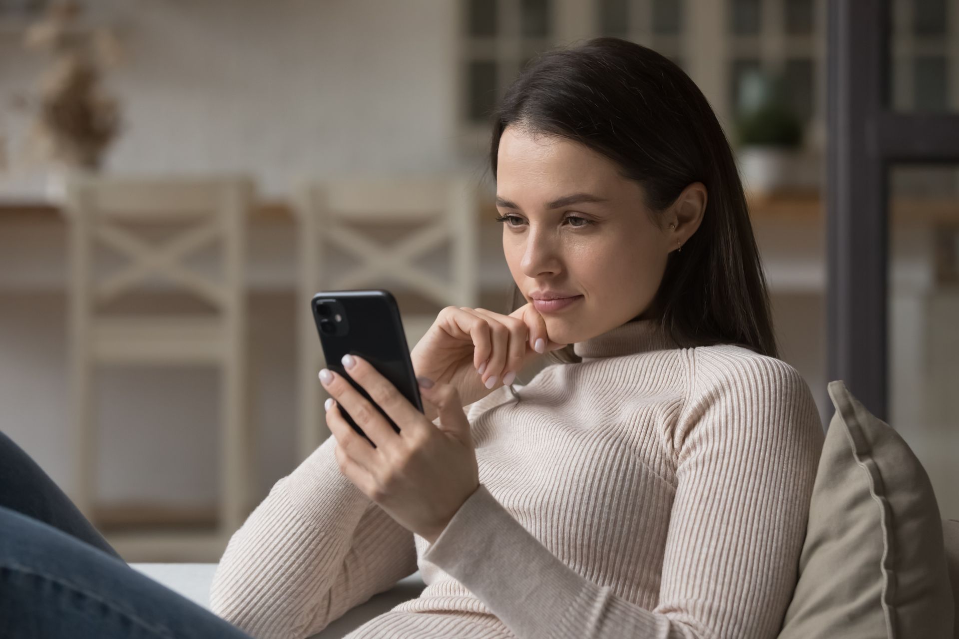 Woman using smartphone at home, researching pregnancy options and accessing confidential support resources