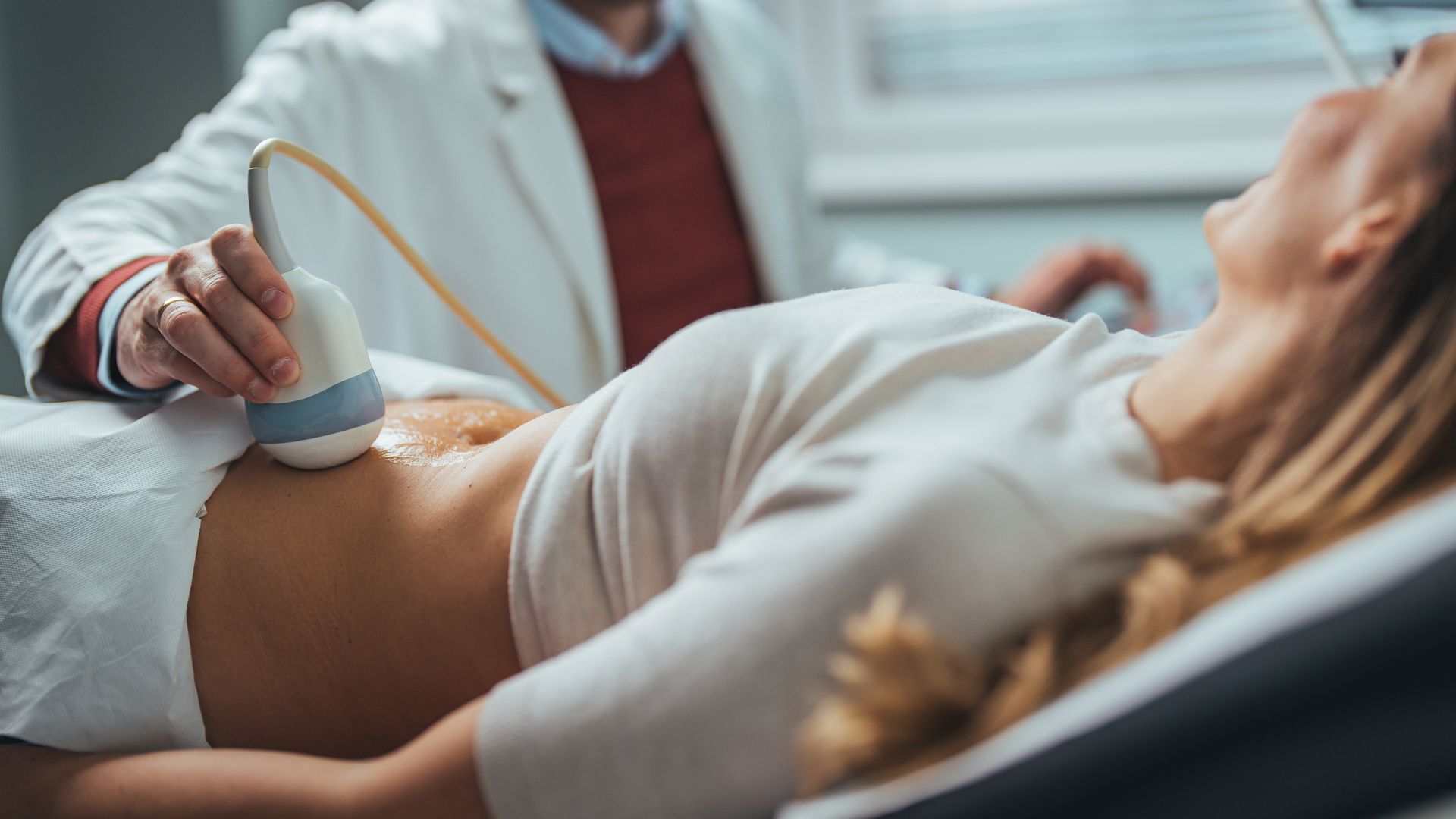 Doctor performing ultrasound on pregnant woman during prenatal checkup in clinic