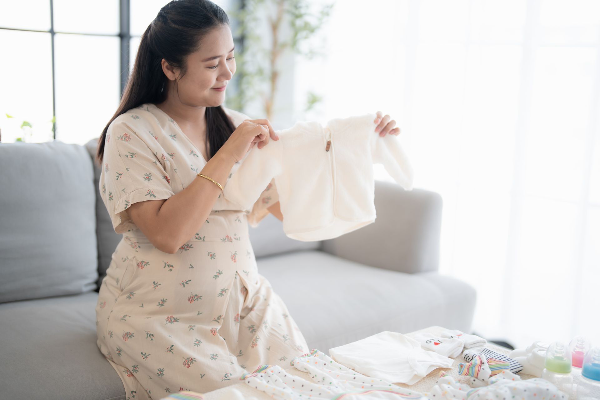 Pregnant woman holding baby clothes, preparing with hope, support, and care for her growing family