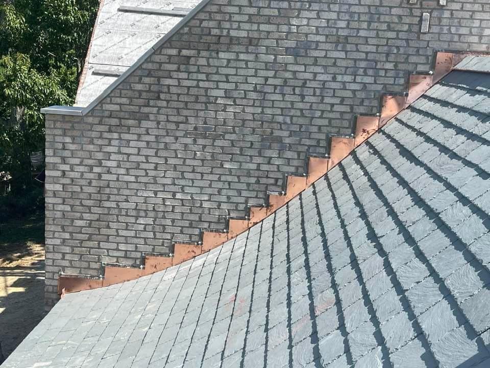 A close up of a roof with a brick wall in the background