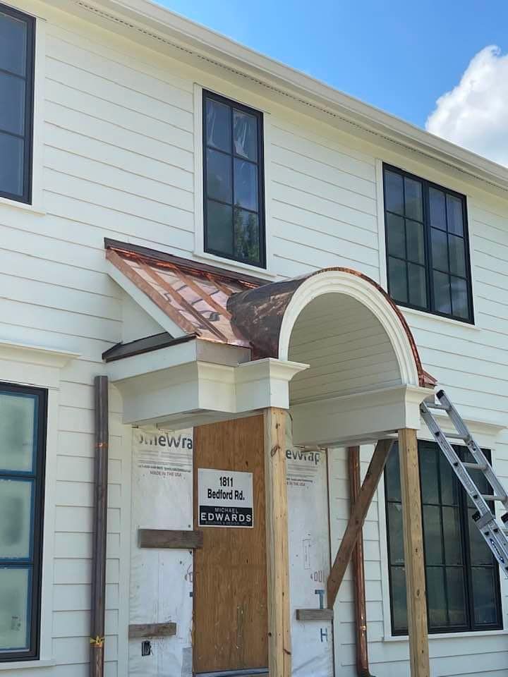 A white house with a copper roof and a wooden door
