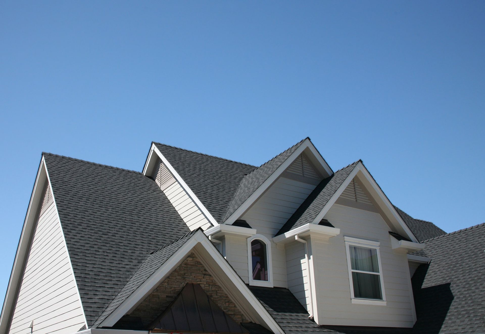 A white house with a black roof and a blue sky in the background