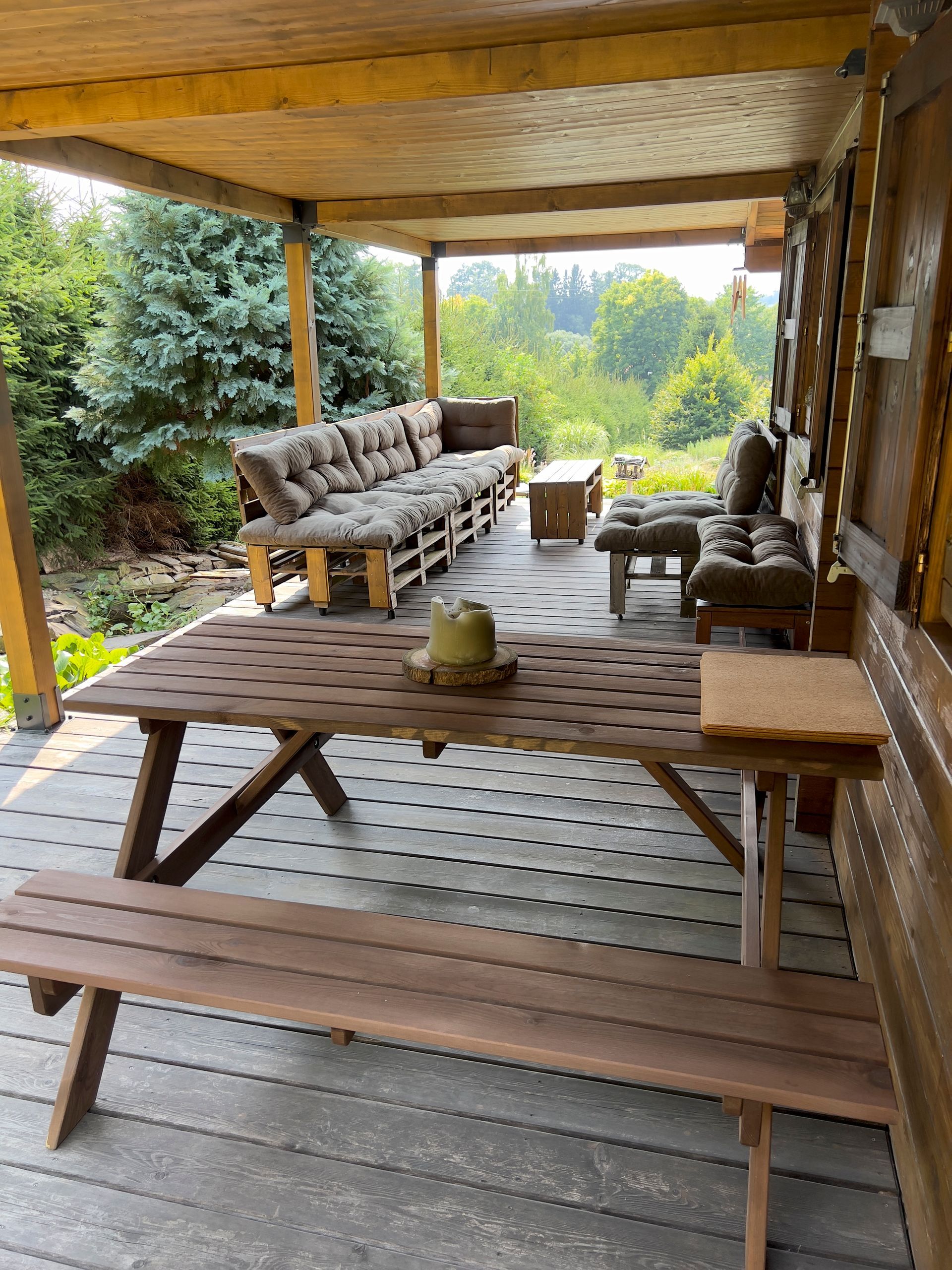 Wooden outdoor patio with seating and a view of trees.