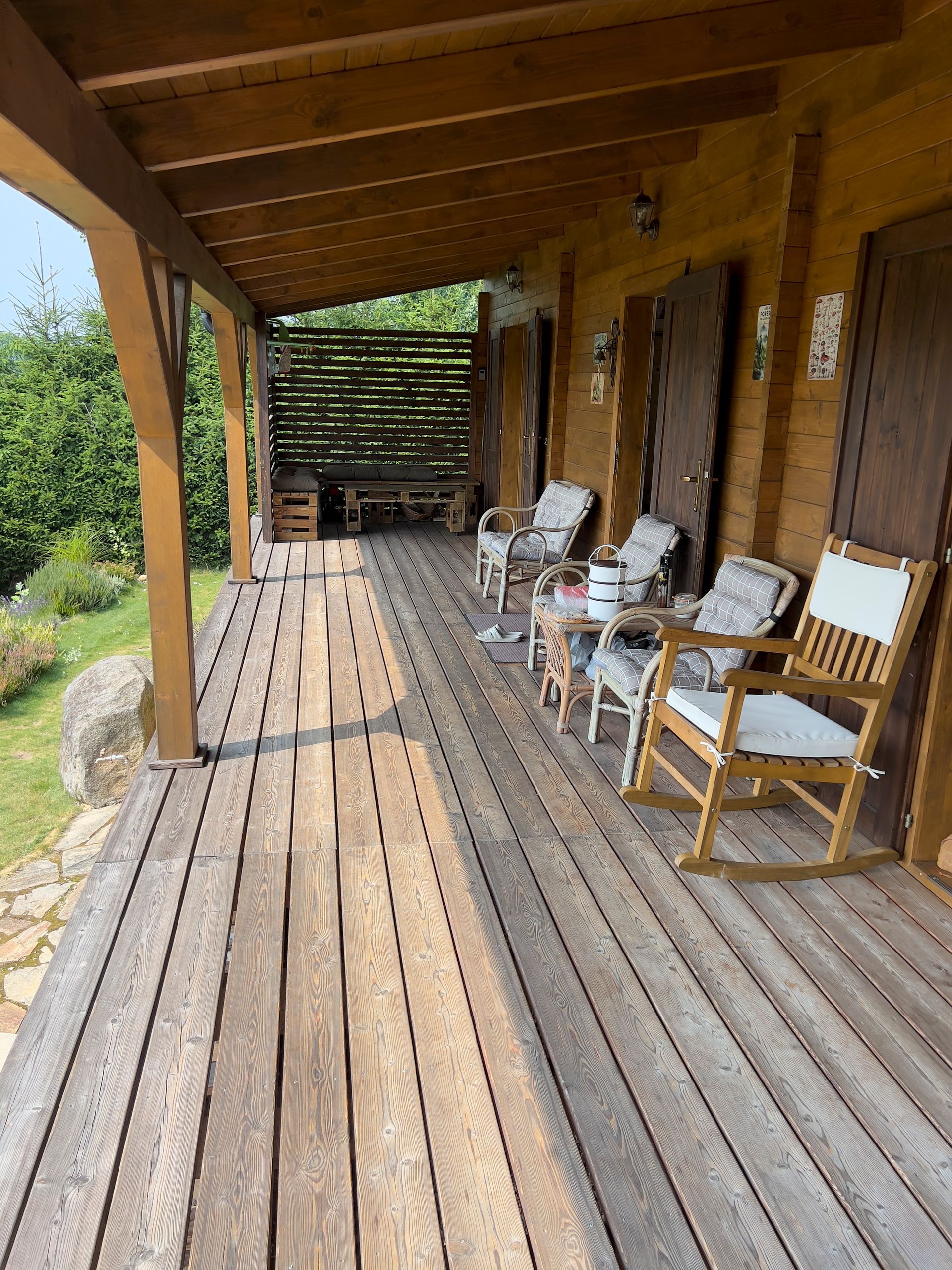 Wooden porch with rocking chairs and doors, a wooden structure. Sunny day.
