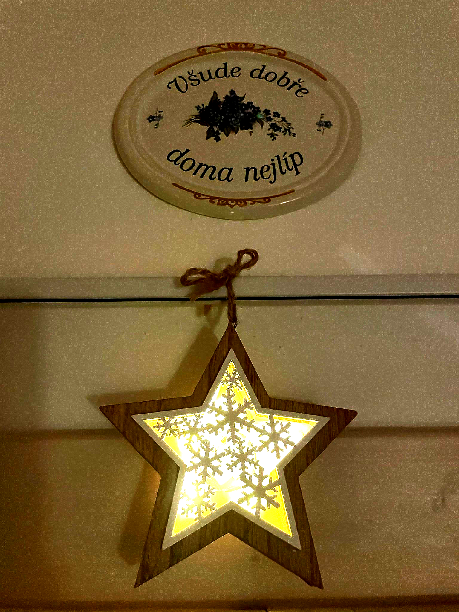 Wooden star-shaped decoration with snowflakes, hanging below an oval sign that reads 