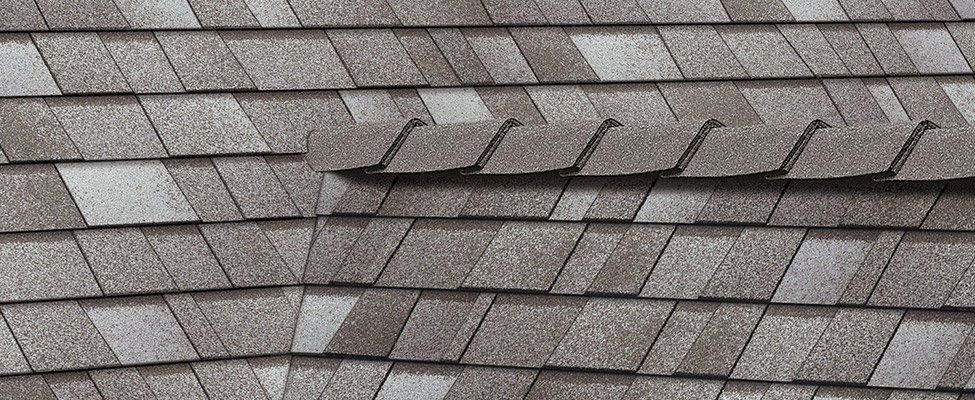Close-up of gray, multi-toned architectural asphalt roof shingles installed in a staggered, overlapping pattern.