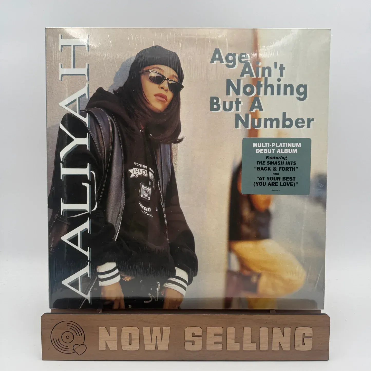 Record album cover of Aaliyah with “Age Ain’t Nothing But a Number” and a “Now Selling” display stand