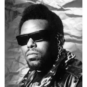 Black-and-white portrait of a person wearing sunglasses, a leather jacket, and a chain necklace.