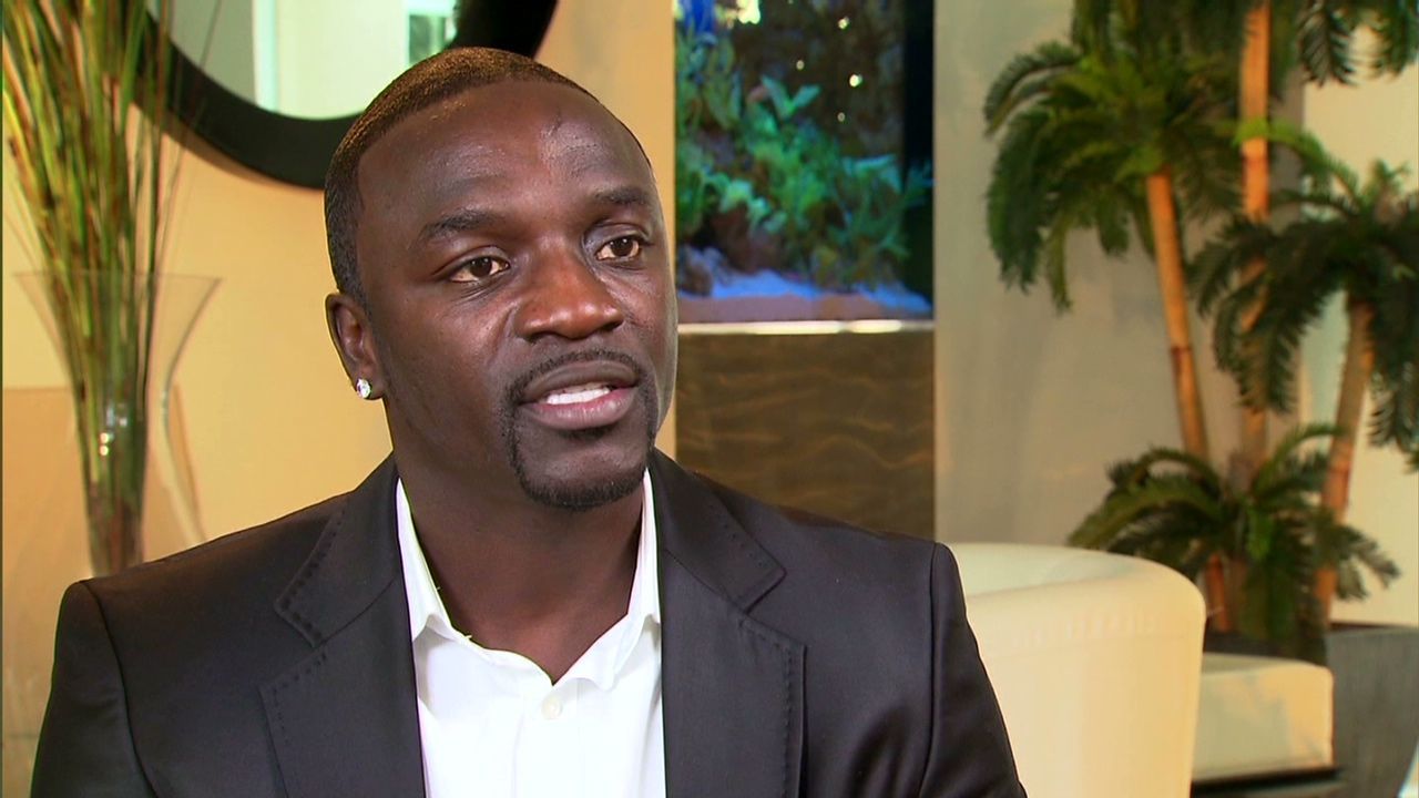 Man in a dark blazer and white shirt speaking in a modern indoor lounge with plants and soft lighting