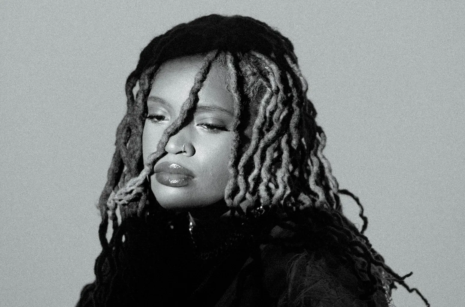 Black-and-white portrait of a person with braided hair against a plain background