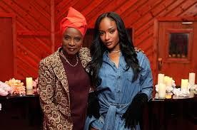Two women posing indoors with candles and a red wood-paneled wall behind them