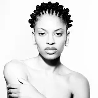 Portrait of a person with short curly hair against a white background, looking directly at the camera