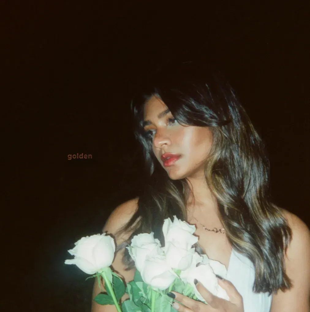 Woman with long dark hair holding white flowers against a dark background