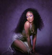 Woman posing in a silver dress against a purple studio backdrop