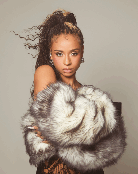 Portrait of a model in a furry gray coat, facing forward with a neutral expression against a plain backdrop
