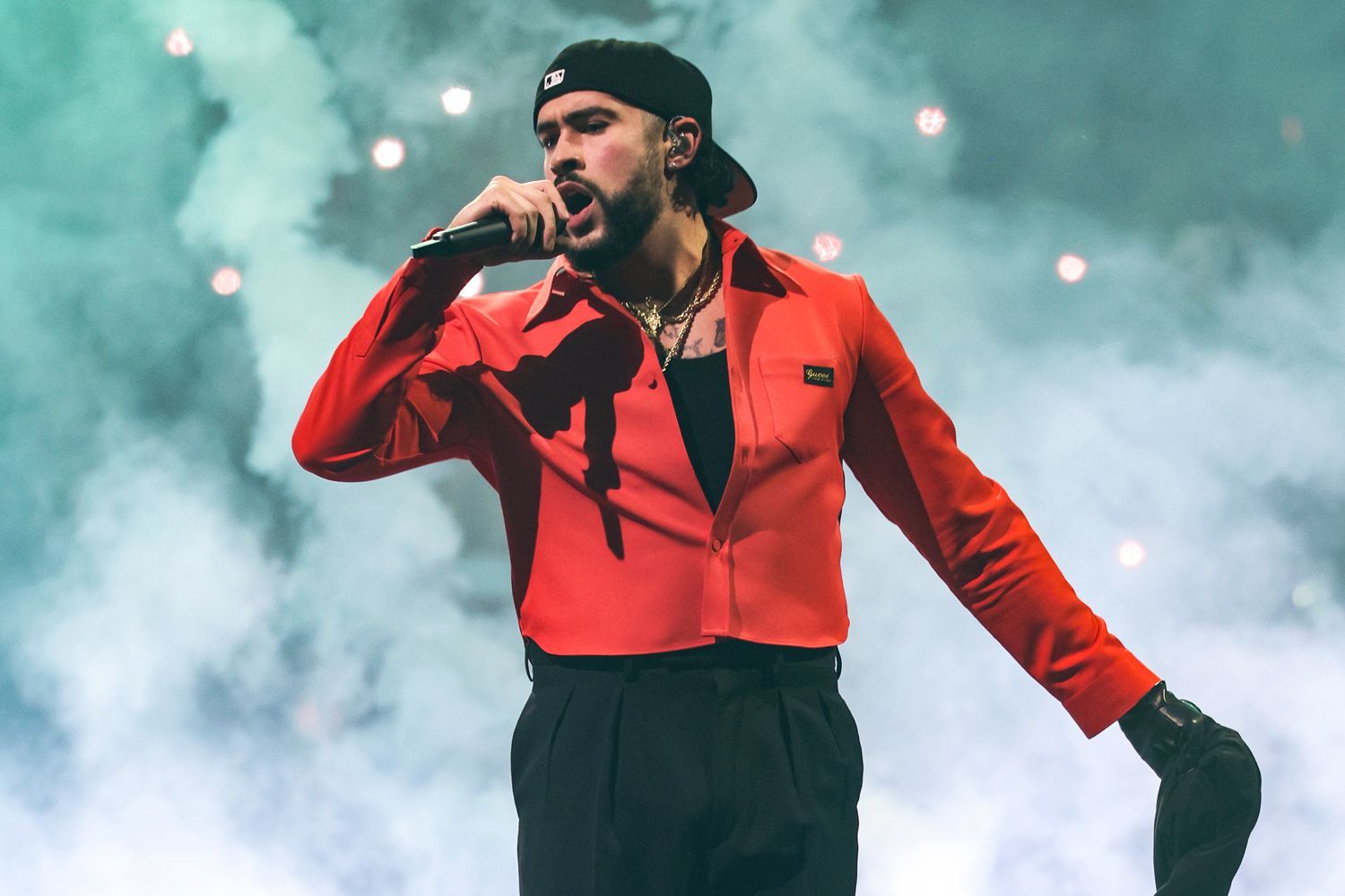 Singer in a red jacket performing onstage with a microphone amid smoky lights