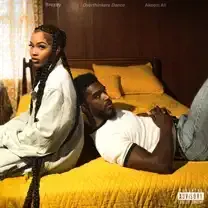 Two people sitting back-to-back on a bed with bright yellow bedding in a warm-toned bedroom.