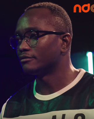 Man wearing glasses and a black-and-white shirt under colorful stage lighting