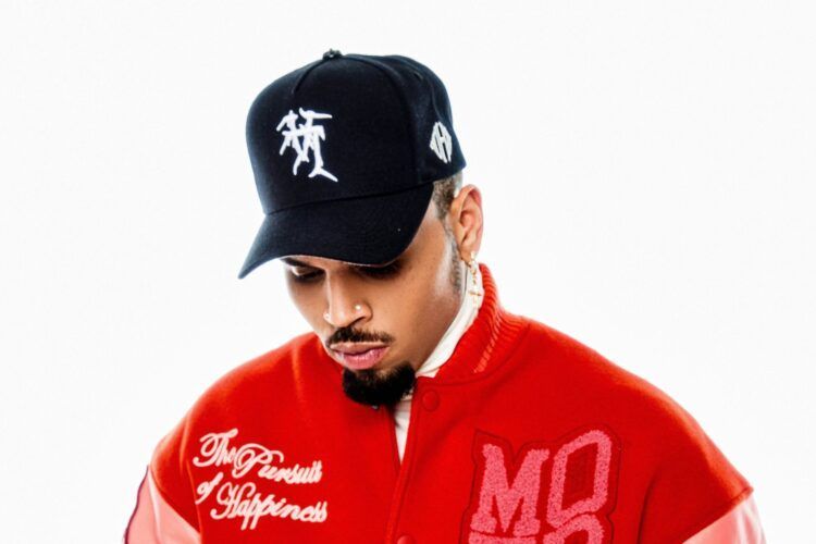 Man in a black cap and red jacket looking down against a white background